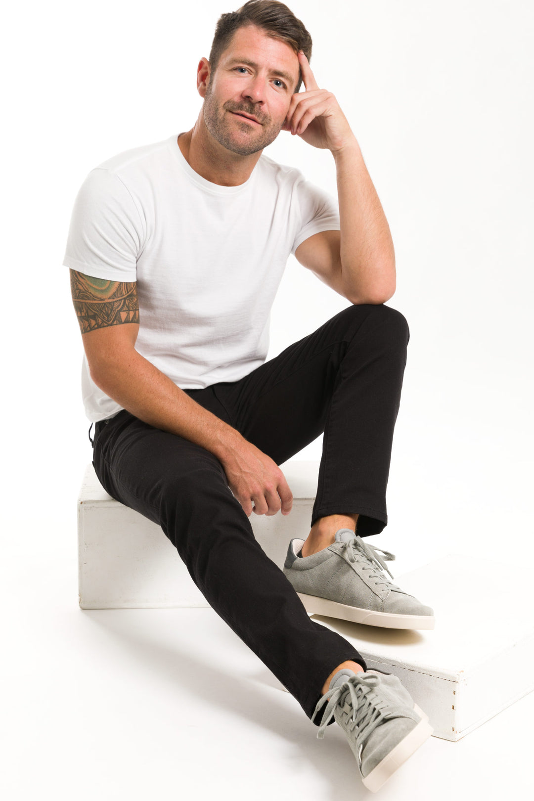 Model wearing Asphalt Wash Explorer Jeans sitting on box